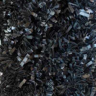 Close-up of black crinkle cut paper shred, deep black zig-zag paper strands for gift basket and box fill