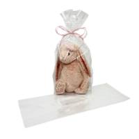 Large clear cellophane side-gusset bag holding a plush bunny tied with pink ribbon, next to an empty flat bag