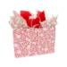 Wide pink paper shopping bag printed with frosted Christmas tree cakes, green and red stars and white snowflakes, and white twisted-paper handles