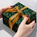 Gift box wrapped in Forest Snowflakes paper with a gold ribbon bow
