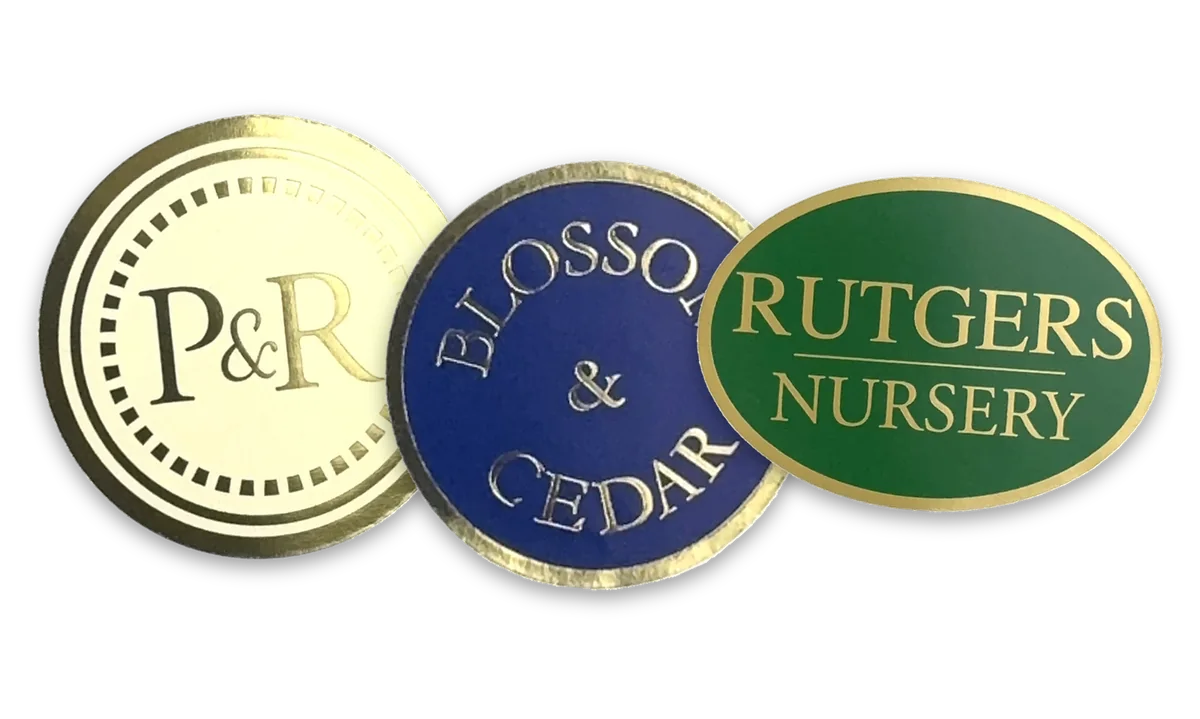 Gold foil hot stamped labels supplied to customers: a bright gold seal, gold on a navy oval and gold on a dark green oval