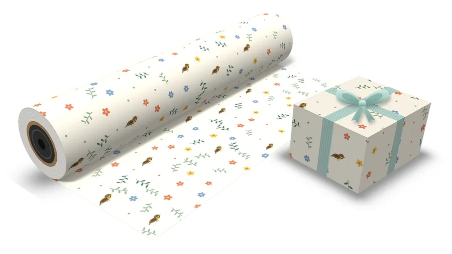 Cream custom gift wrap with wildflowers, leafy sprigs and small songbirds, on a matte roll and a wrapped box with a sage ribbon
