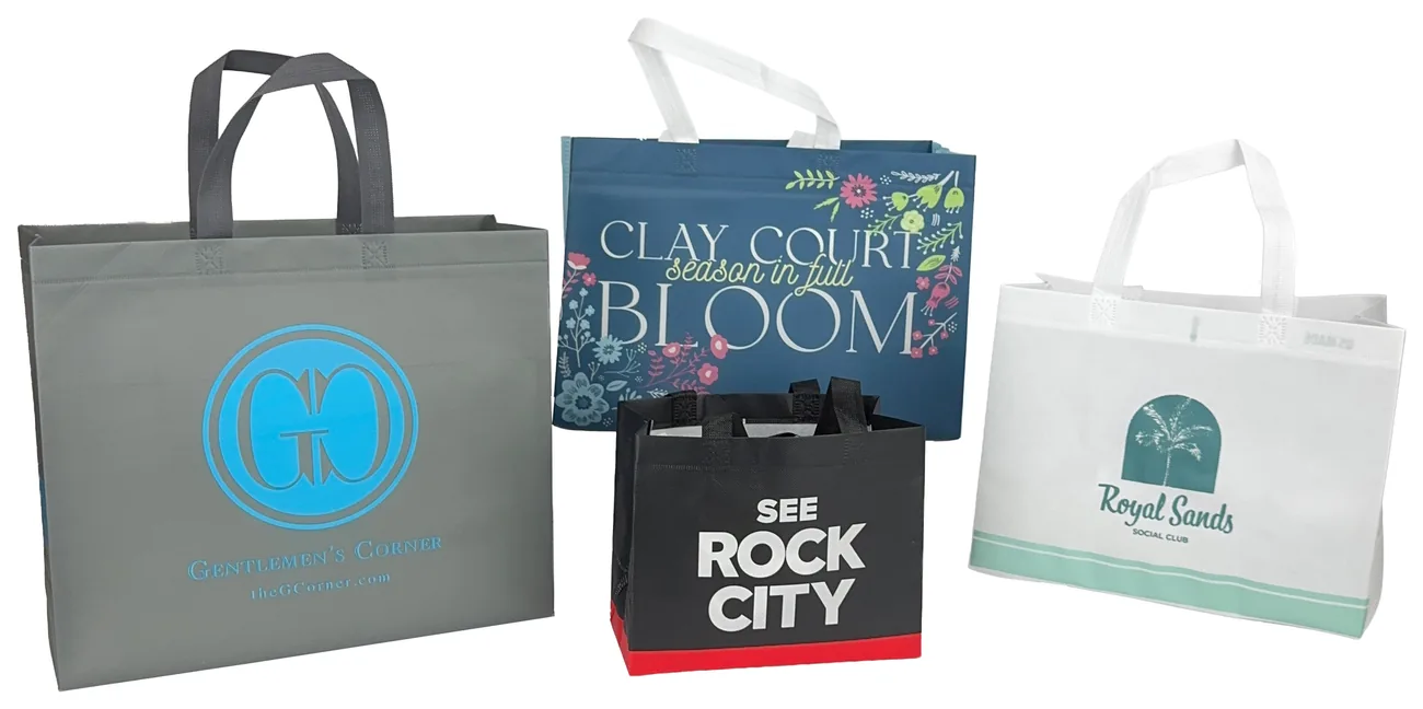 Four custom heat sealed tote bags, a grey bag with a blue monogram, a navy floral bag, a small black and red bag and a white bag with a palm tree logo