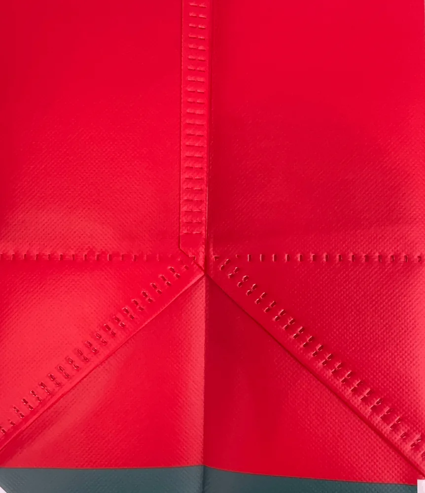 Close up of a red heat sealed laminated tote bag showing the welded side seam and bottom gusset with no stitching