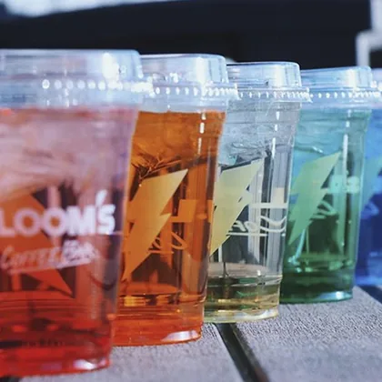 Row of custom printed clear plastic cups with colored drinks for a coffee bar