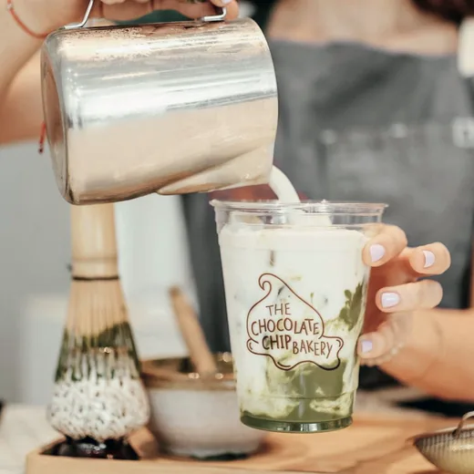 Custom printed clear plastic cup for a bakery being filled with a matcha latte
