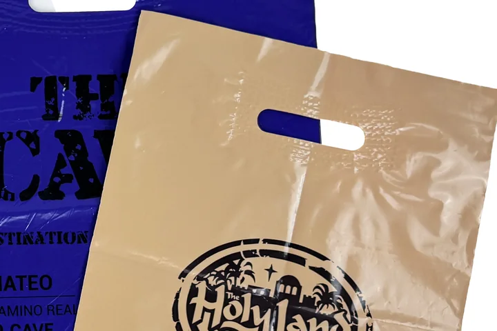 Close up of a patch handle on a tan plastic bag showing the embossed reinforcing patch around the hand hole