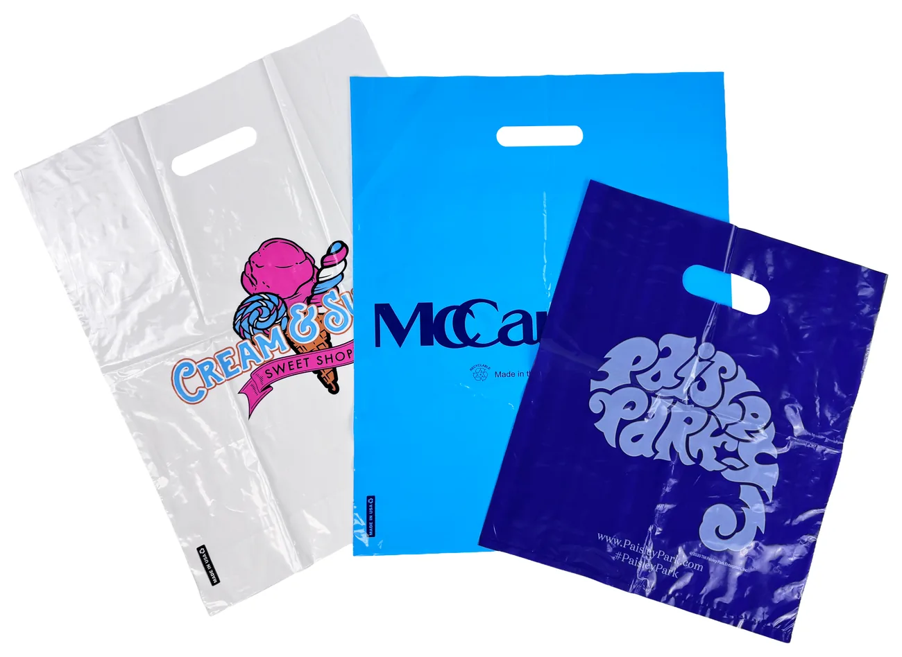 Three custom printed die cut handle plastic bags: a clear bag with a four color sweet shop logo, a light blue bag with a navy logo and a purple bag with a lavender logo