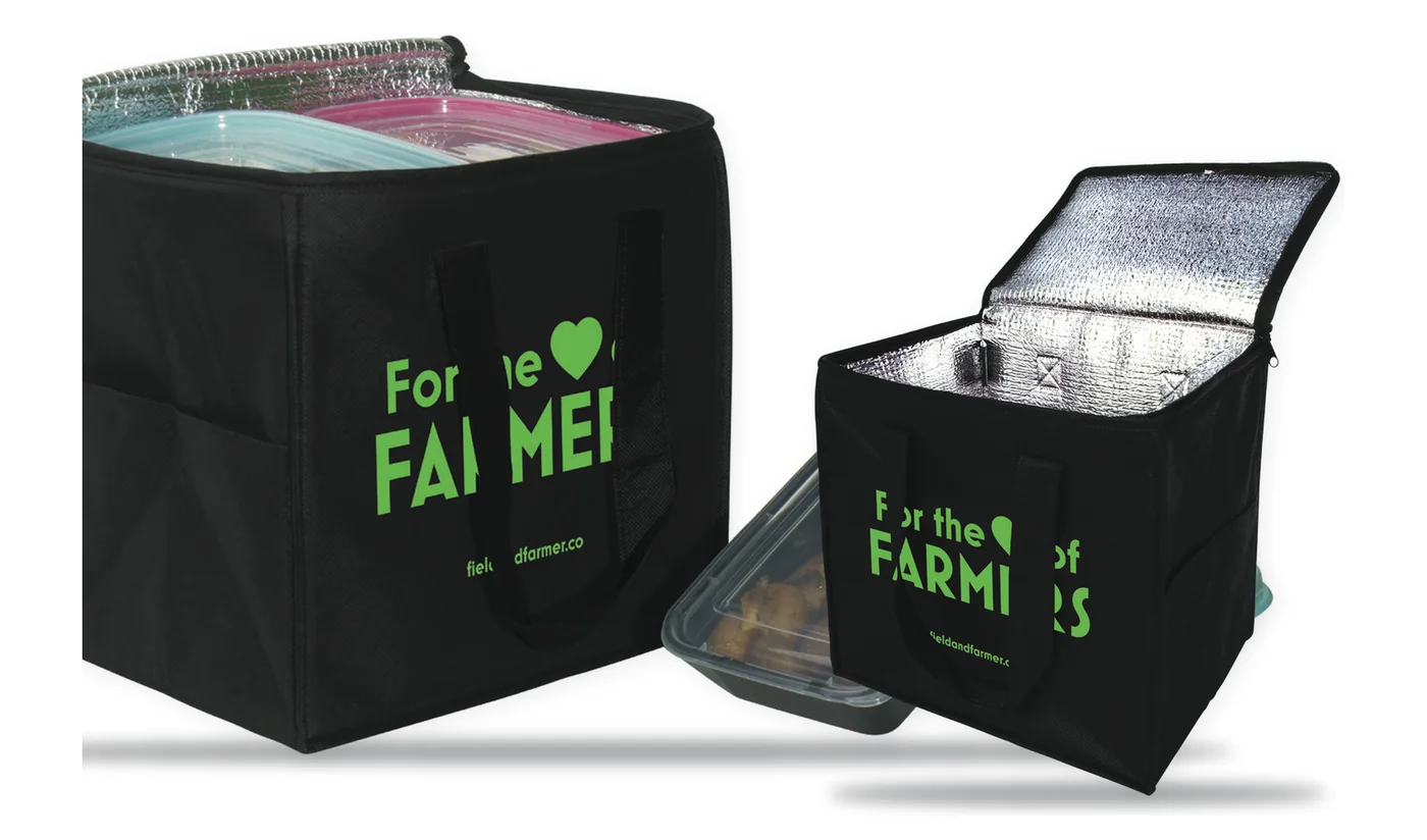 Two custom printed black insulated cooler totes with a green farm logo, one open to show the foil lining and food containers