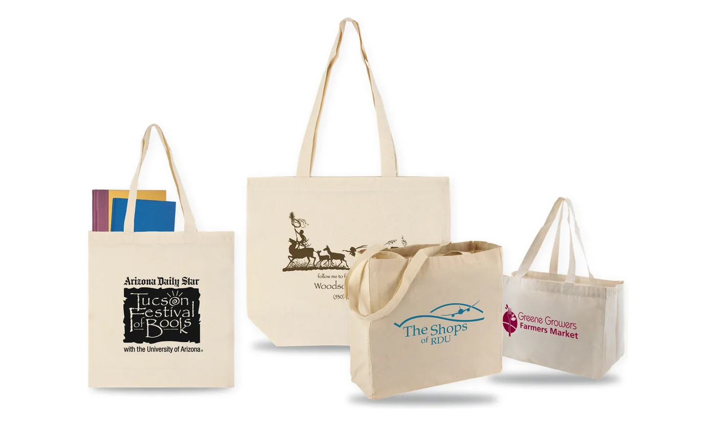 Four custom printed natural cotton tote bags, two flat totes and two gusseted market totes, printed with festival, shop and farmers market logos
