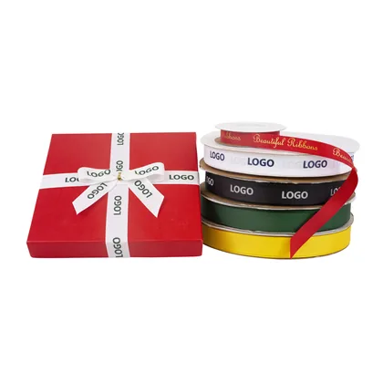 Red gift box tied with white screen printed logo ribbon beside stacked printed rolls