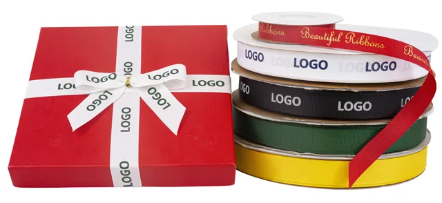 Red gift box tied with white screen printed logo ribbon beside printed grosgrain rolls