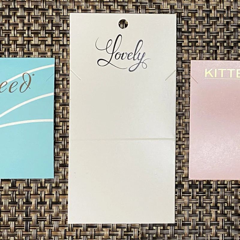 Flat and foldover custom necklace cards in aqua, ivory, and pink with hot-stamped and printed brand logos
