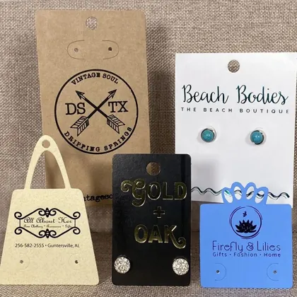 Custom printed earring cards in kraft, black, white, and blue with hot-stamped logos and stud earrings
